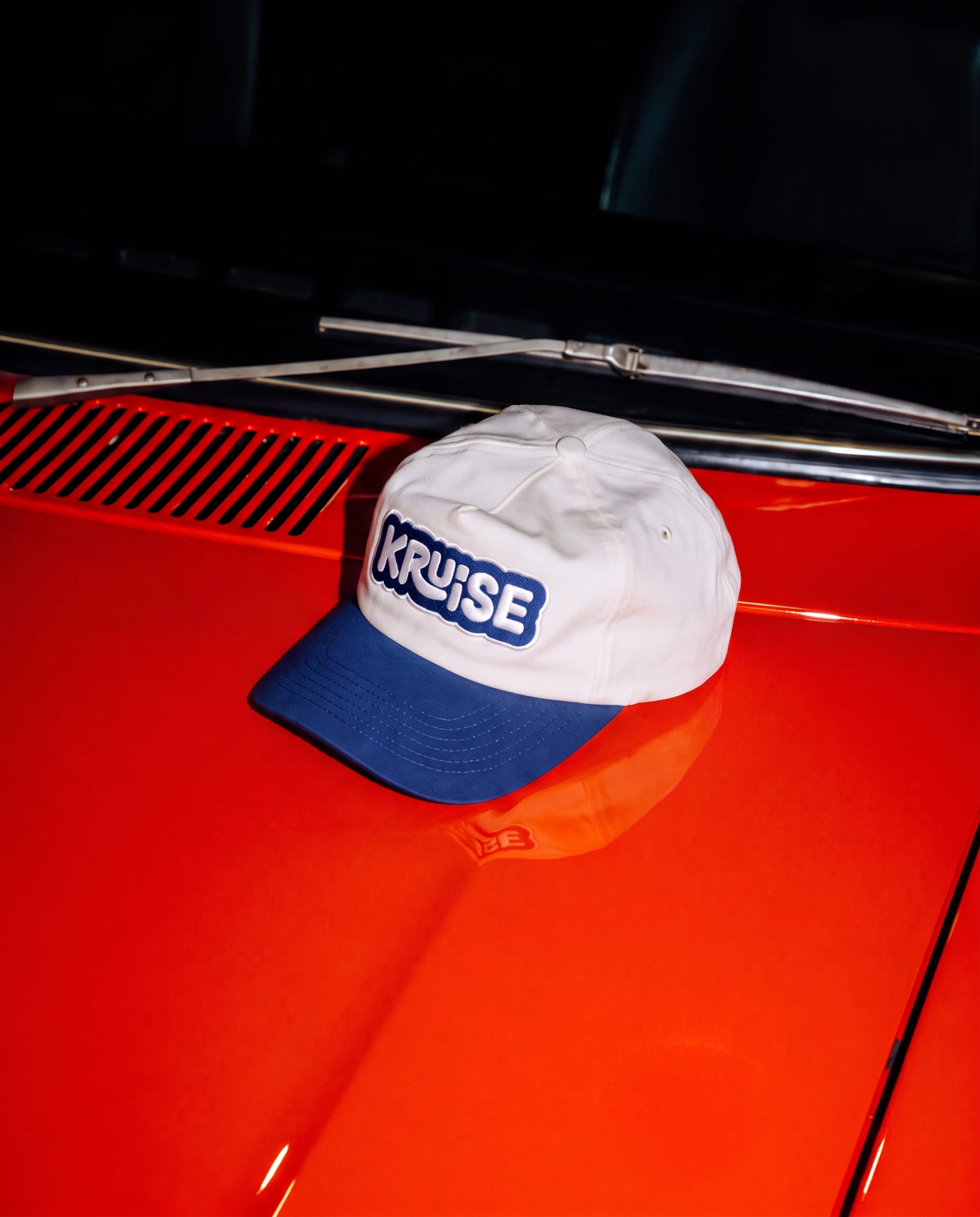 Kruise two-tone cap on a red car bonnet
